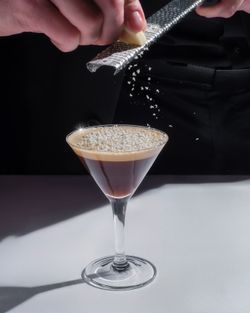 Cocktail in a martini glass topped with grated garnish being prepared by a catering chef at Cuisine Boulud New York.