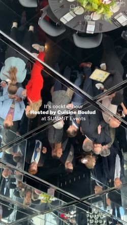 Guests mingling at a cocktail hour event hosted by Cuisine Boulud New York, reflected in mirrors above.