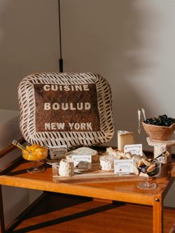 Cheese platter with labeled varieties and a Cuisine Boulud New York sign on a wooden table