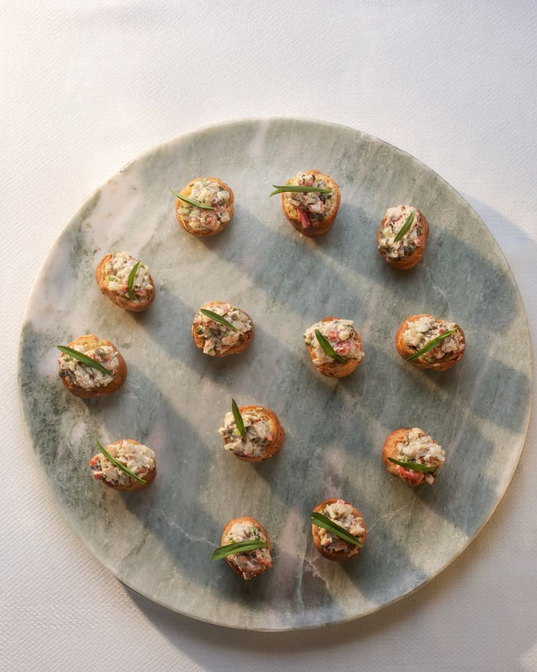 Exquisite canapé arrangement featuring gourmet toppings on a decorative platter, ideal for luxury catering events.